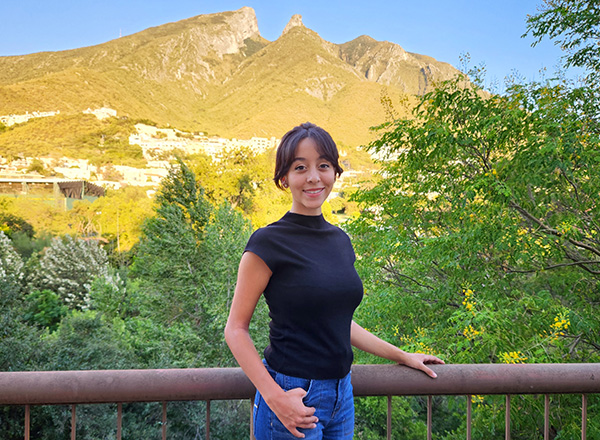 Andrea Herrera standing in front of a mountainous scene. 