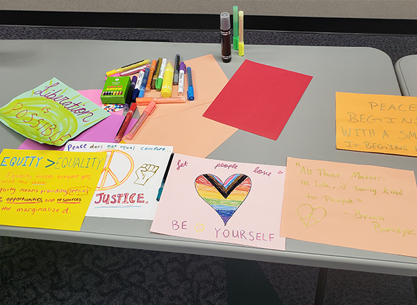 Art supplies, paper, and protest posters laid out on a table.