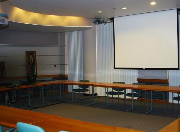 Photograph of Ghafari Conference room showing extended projection screen and chairs arranged around tables