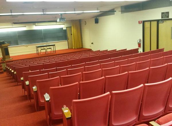 Photograph of the Liberal Arts Auditorium, containing rows of red seats with attached writing surfaces